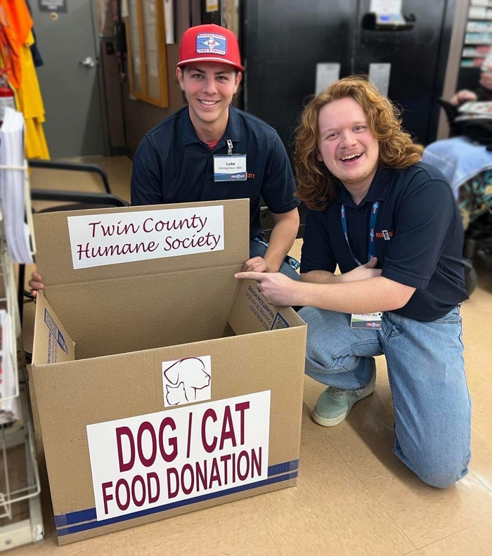 two people with pet food donation box
